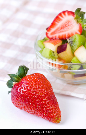 Strawberry and fruit salad in white plate on tablecloth, close up Stock Photo
