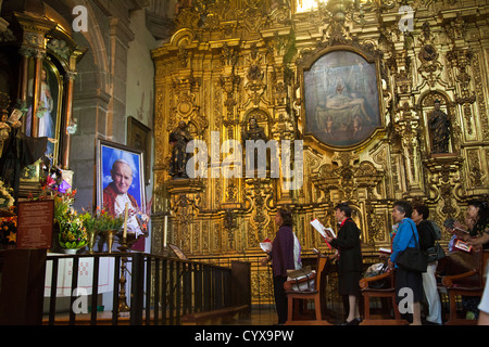 Women praying to/ for Pope John Paul II at a side chapel in Metropolitan Cathedral of the Assumption of Mary of Mexico City DF Stock Photo
