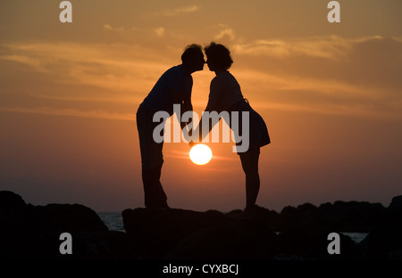 A couple by sunset on a pier looking each other romanticly in the eyes Stock Photo