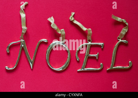 Hanging brass letters spelling Noel isolated on red background Stock Photo