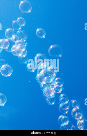 Soap bubbles. Air is blowing through a ring, covered with soapy water. Made with a children toy, a soap bubble machine. Stock Photo