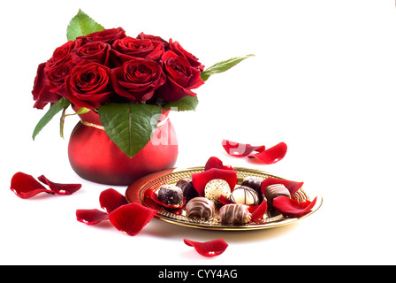 Beautiful roses in pot with gold plate of chocolates Stock Photo