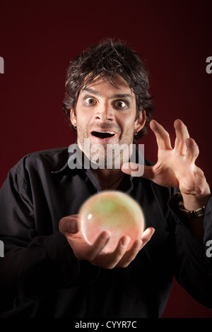 Excited fortuneteller gazes over a crystal ball Stock Photo