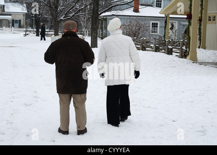 Elderly couple walking on snowy street Stock Photo