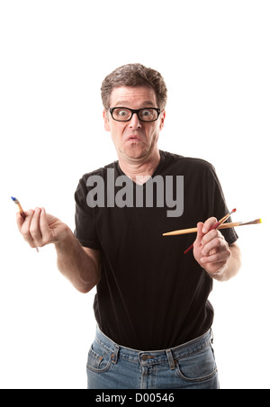 A puzzled artist holding paintbrushes on a white background Stock Photo