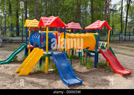 Plastic multi-colored children's playground in a pine park on a sunny day Stock Photo