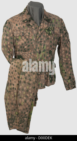 A model 43 camouflage suit of the Waffen-SS,Field blouse with one side printed in 'Erbstarn' pattern camouflage with bluish painted metal buttons(one missing),interior reinforcements and first aid dressing of greyish herringbone pattern artificial silk. Size stamping barely discernible. Supplemented,but original BeVo sleeve eagle,sand-coloured weave on a black base. Trousers of like material with metal buttons,the inner reinforcements of grey cotton,white pocket sacks. Metal parts corroded. Small defects,repaired areas,historic,historical,1930s,20th,Additional-Rights-Clearences-Not Available Stock Photo