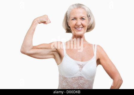 Portrait of senior woman flexing muscles against white background Stock Photo
