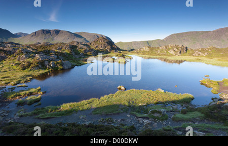Sun rising over Innominate Tarn with Kirk Fell in the distance. Lake district, England, UK. Stock Photo
