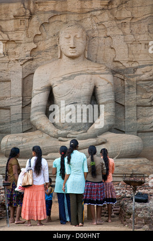 Women worshiping a seated Buddha. Gal Vihara. Polonnaruwa ancient city. Sri Lanka Stock Photo