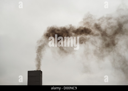 Dark black smoke from the chimney on a cold, cloudy day. Stock Photo