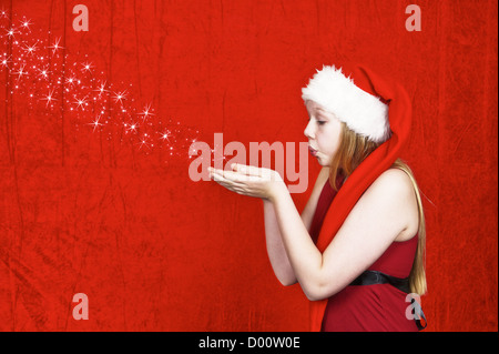 Beautiful girl blowing stars from the palm of her hands on red background Stock Photo