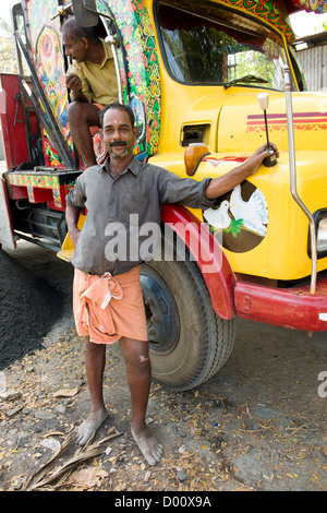 Man posing next to the brightly coloured cab of his lorry, Alappuzha (Alleppey), Kerala, India Stock Photo