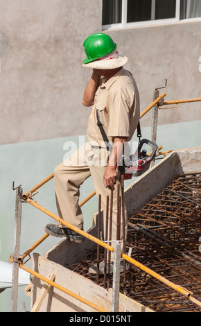 Crane operator talking on mobile phone on building site in Spain Stock Photo