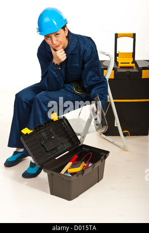 Confused workers woman sitting on step ladder with tool box open Stock Photo