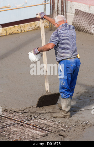 Construction worker smoothing cement on building site in Spain Stock Photo
