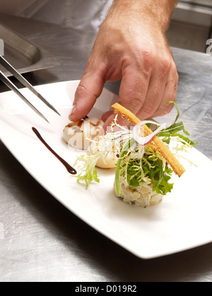 Chef putting the finishing touch to a nice scallops dish course in his professional kitchen Stock Photo