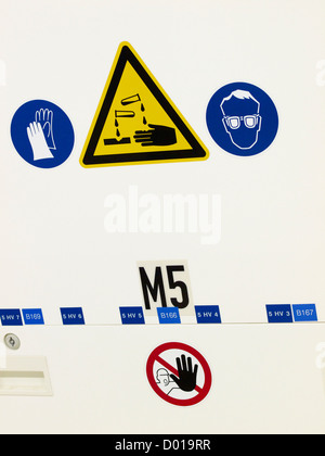Various industrial warning stickers, gloves needed, danger corroding fluids, eye protection needed. Stock Photo