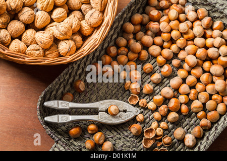 Hazelnuts and walnuts with in wicker basket on old table Stock Photo