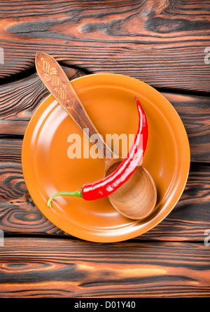 Pepper in a plate and spoon on a wooden background Stock Photo