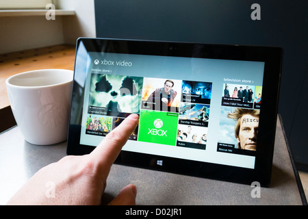 Man using Microsoft Surface rt tablet computer to browse movies in Microsoft video store online Stock Photo