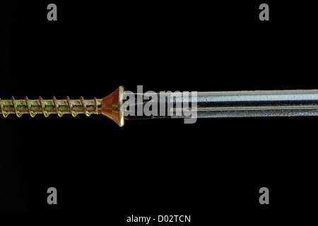 Close-up of a screwdriver driving a brass screw - 36MP image Stock Photo
