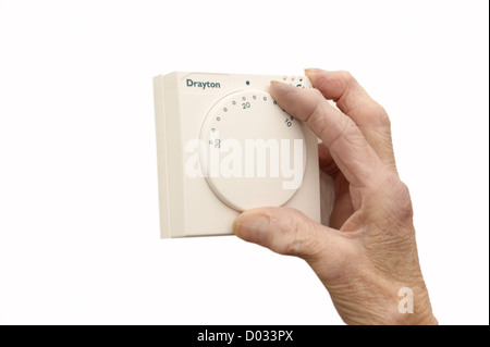 elderly woman lowering the thermostat on the central heating control to combat global warming and climate change Stock Photo