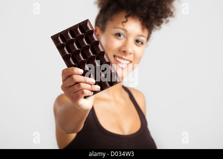 Beautiful African woman holding a huge dark chocolate bar Stock Photo