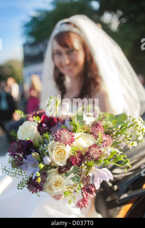 Out of focus bride displaying her floral bouquet to the camera on her wedding day. Stock Photo