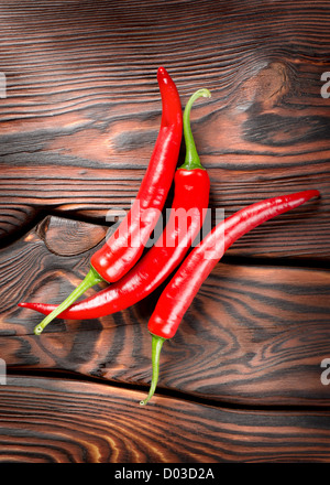Three red chili peppers on a wooden background Stock Photo