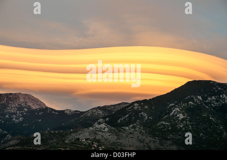 Lenticular clouds forming at sunset over the Taygetus mountains, in the Outer Mani, Peloponnese, Greece. Stock Photo