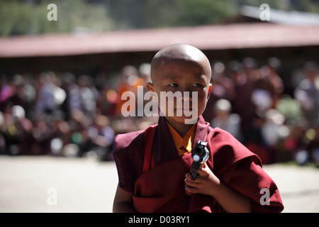Little monk standing with a toy gun performing art at a festival in Bhutan Stock Photo