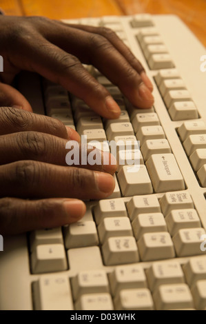 African man's hands typing on grey computer keyboard Stock Photo