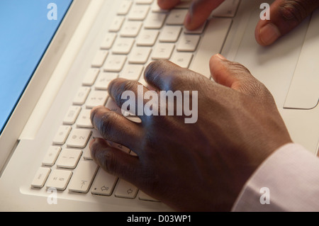 African man's hands typing on grey computer keyboard Stock Photo