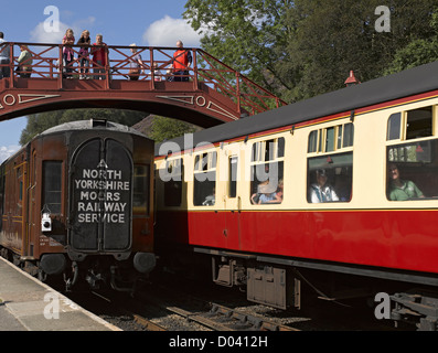 People visitors watching railway train passenger coaches leaving Goathland Station in summer NYMR North Yorkshire England UK United Kingdom Britain Stock Photo
