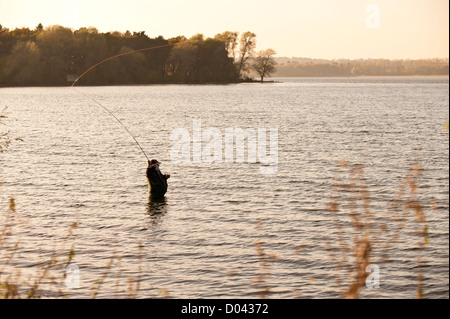An angler fly fishing in Hanningfield Reservoir in Essex. Stock Photo