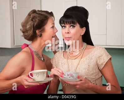 Retro styled Caucasian woman shares a secret with her friend Stock Photo