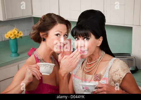Middle-aged retro styled Caucasian woman whispers secret to her friend Stock Photo