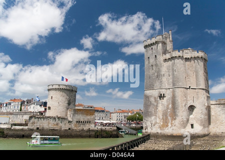 A water taxi exiting between the twin towers of the 'Vieux Port' or old harbour in La Rochelle Stock Photo