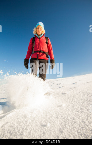 A woman walking in deep snow on the summit of Red Screes in early November, Lake District, UK. Stock Photo