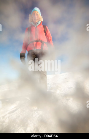 A woman walking in deep snow on the summit of Red Screes in early November, Lake District, UK. Stock Photo