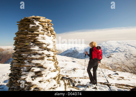 A woman walking on the summit of High Bakestones on the side of Fairfield in early November snow, Lake District, UK. Stock Photo