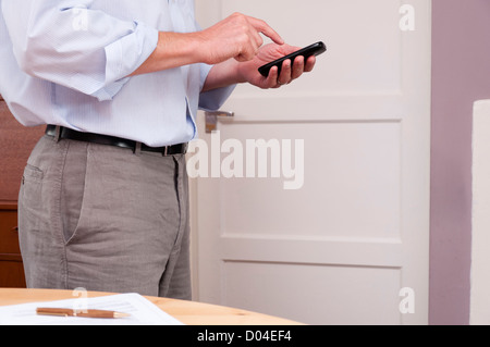 Businessman working at home using a smartphone. Stock Photo