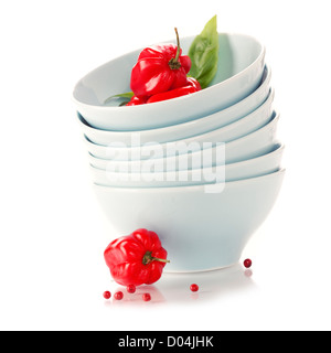 Stack of bowls and red peppers over white Stock Photo