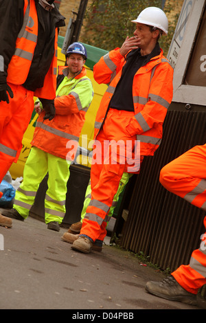 Construction workers taking a cigarette break, in their orange safety wear, London, 8th November 2012 Stock Photo