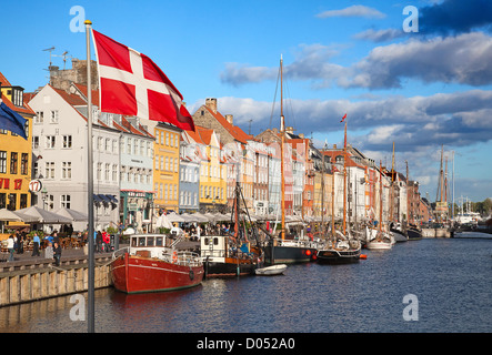 COPENHAGEN, DENMARK - AUGUST 25: Unidentified people enjoying sunny weather in open cafees of the famous Nyhavn promenade on August 25, 2010 in Copenhagen, Denmark. Nyhavn district is one of the most famous landmark of Copenhagen popular amoung turists and local people. Stock Photo