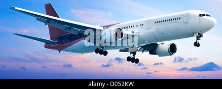 Aircraft is maneuvering in a sunset sky. Panoramic composition. Stock Photo