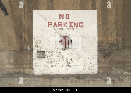 red no parking sign painted on concrete wall on top of white square with fire hose connection Stock Photo