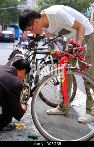 Shanghai China,Chinese Dianchi Road,Huangpu District,bicycle,bicycling,riding,biking,rider,repair,repairman,Asian man men male adult adults,China12100 Stock Photo