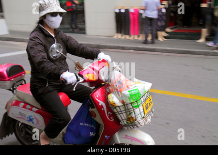 Shanghai China,Chinese Huangpu District,Sichuan Road,Asian woman female women,breathing face mask,electric motor scooter,riding,no helmet,China1210060 Stock Photo